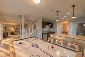 A spacious living area with a foosball table, a kitchen with granite countertops, and a dining area with a table and chairs.