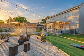 Un patio trasero con zona de estar, mobiliario exterior y una terraza cubierta.