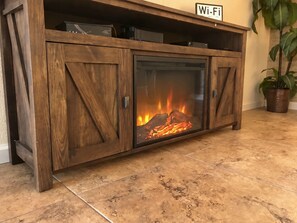 Un mueble de madera con puerta de cristal que exhibe una chimenea.