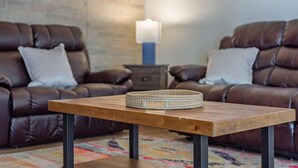 A living room with two brown leather sofas, a wooden coffee table, and a lamp on a side table.
