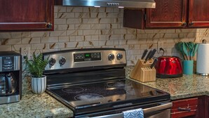 A kitchen with a stainless steel stove, wooden cabinets, a coffee maker, and a toaster.
