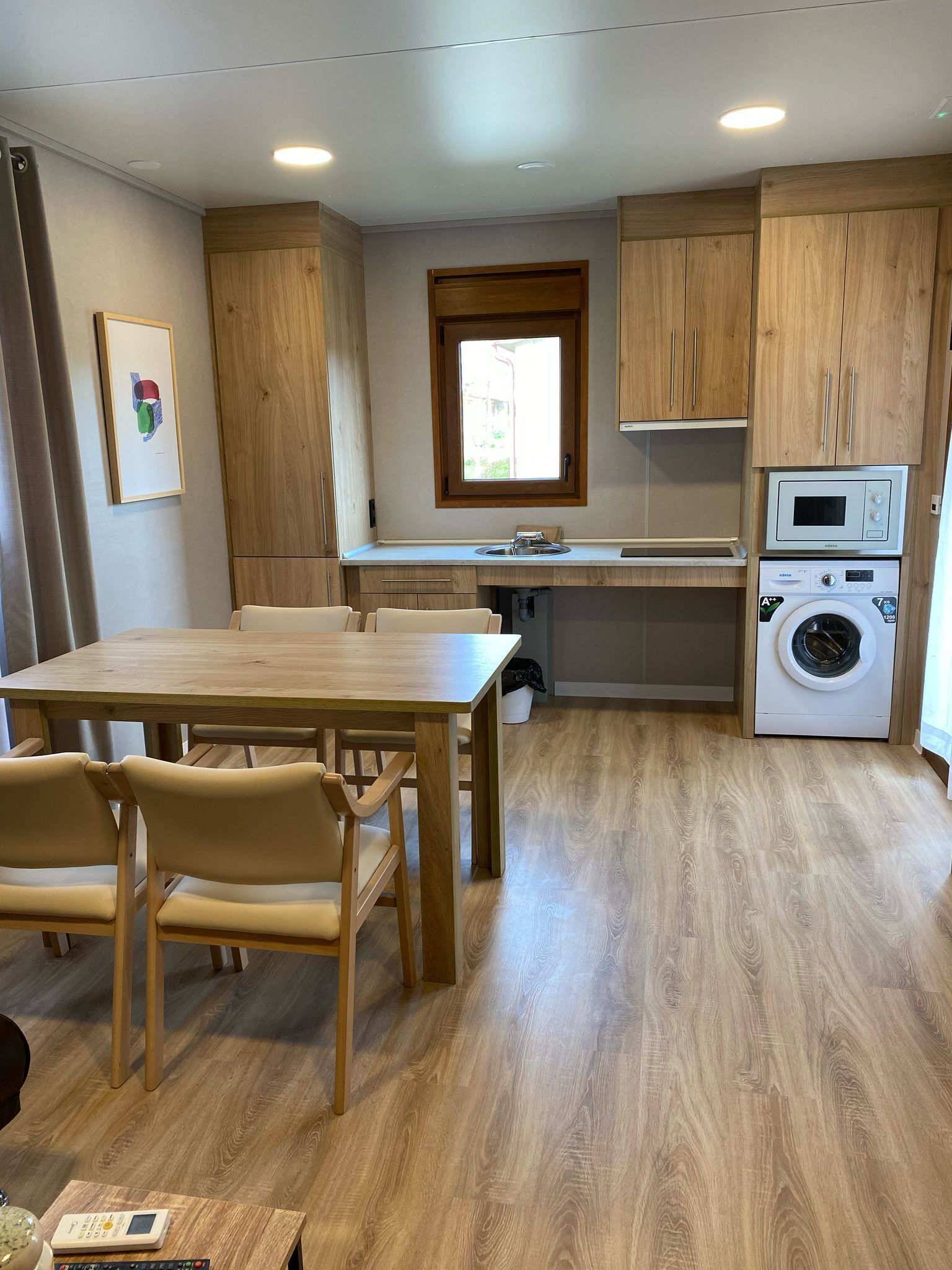 Eine moderne Küche mit Holzausstattung, einer eingebauten Mikrowelle und einer Waschmaschine.