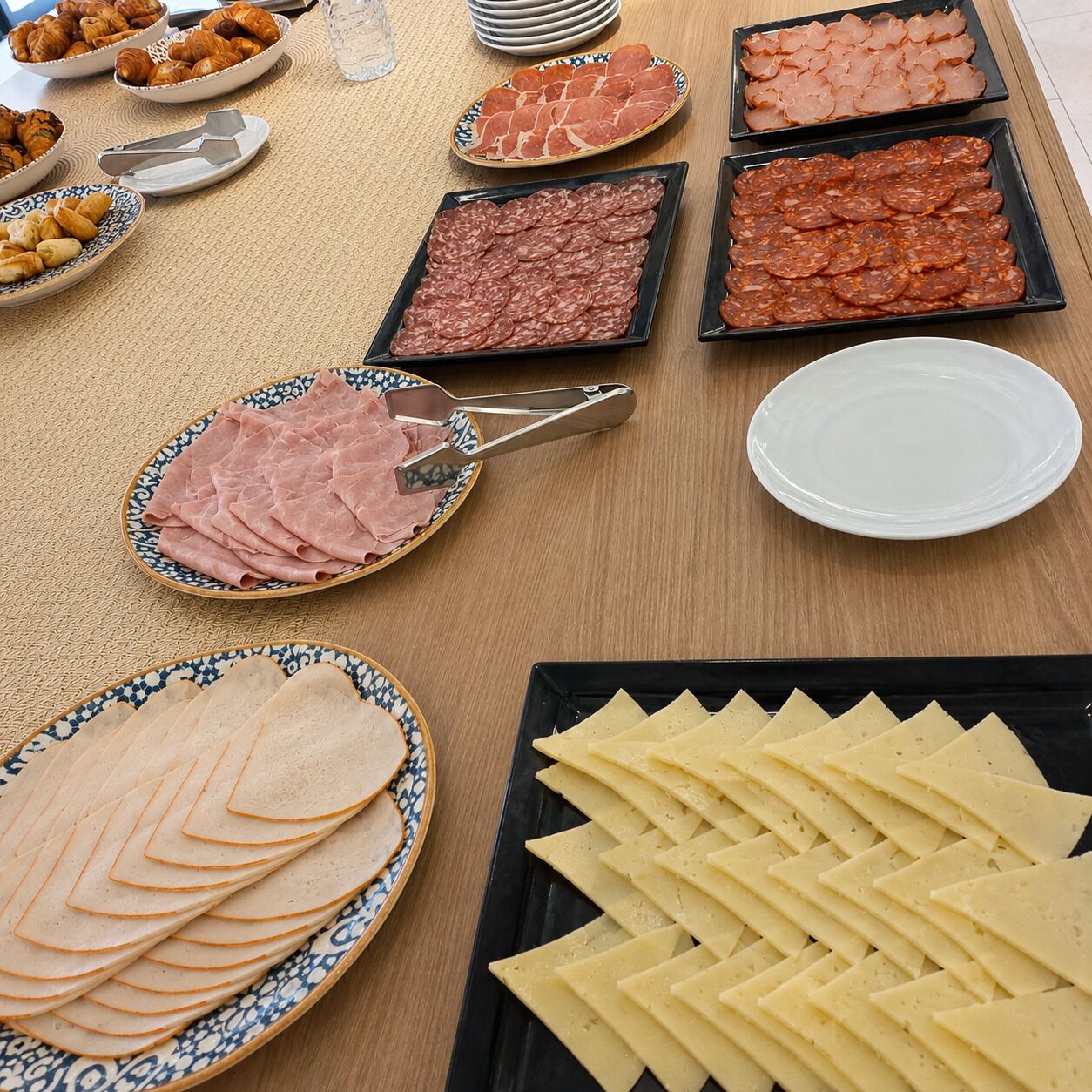 Una mesa con diversos alimentos, incluyendo embutidos y quesos.
