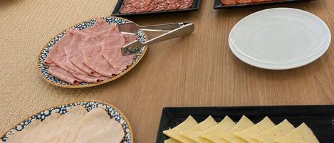 Una mesa con diversos alimentos, incluyendo embutidos y quesos.