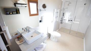 Un baño moderno con un lavamanos grande, inodoro y ducha con mampara de vidrio.