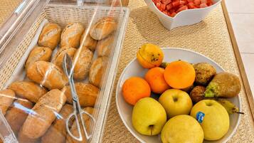 A buffet table with various food items including bread, fruits, and a bowl of watermelon.