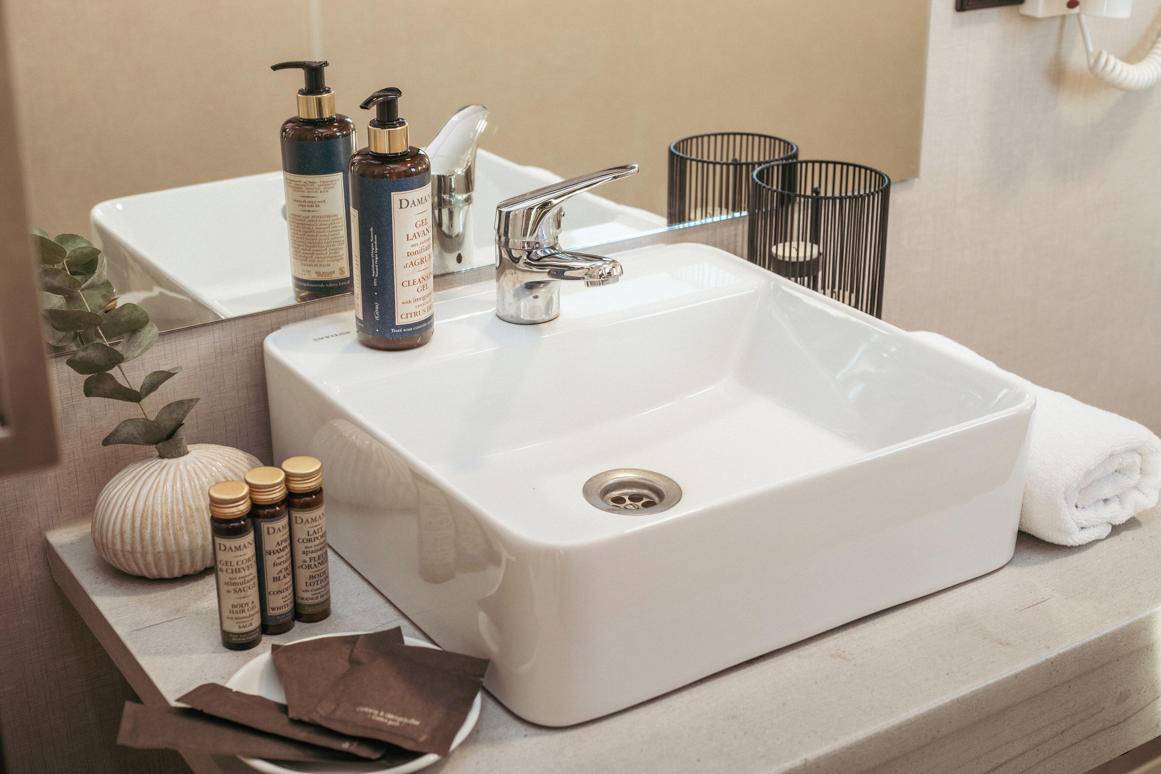 A bathroom with a white sink, a mirror, and toiletries.