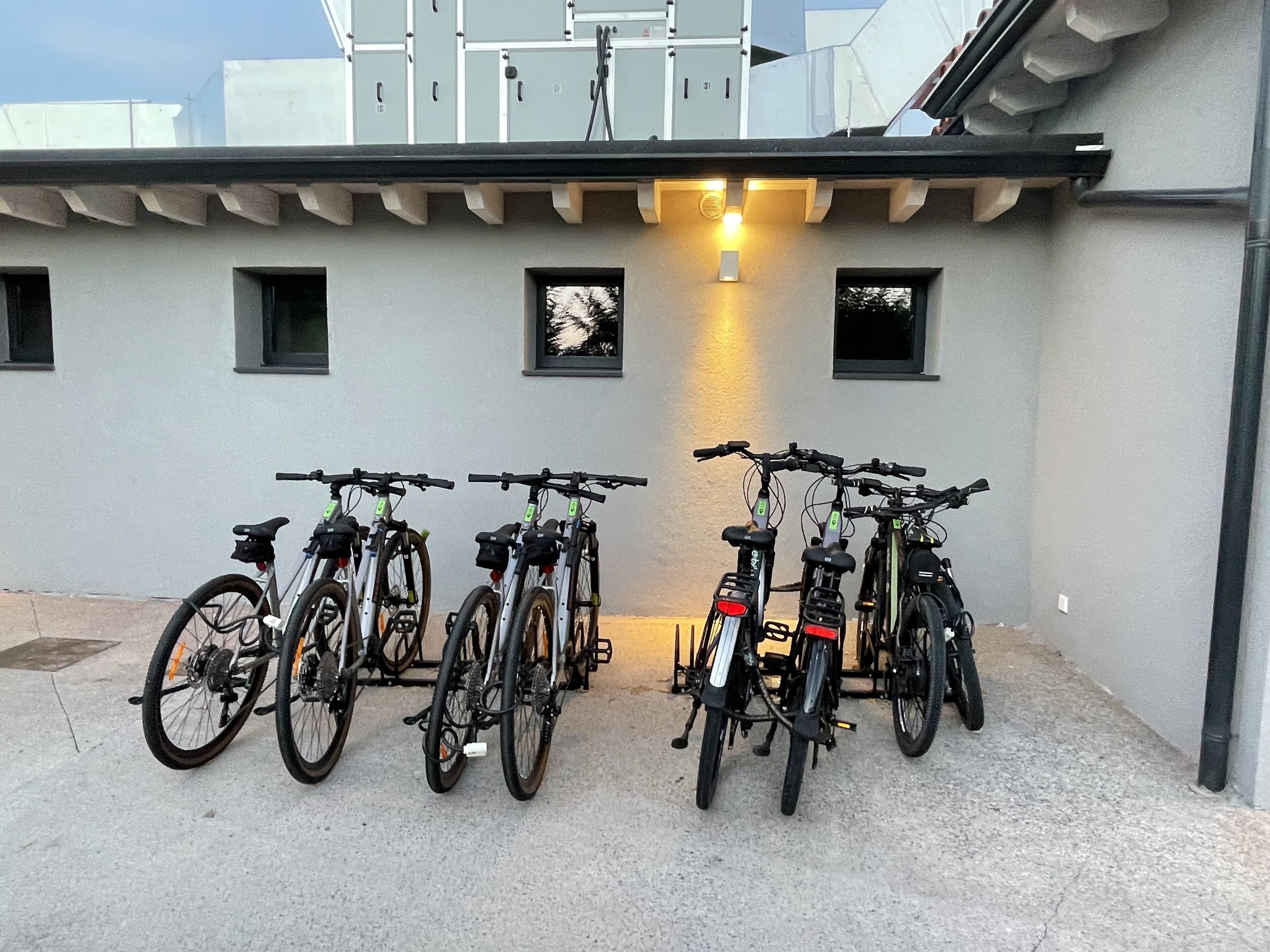 Des vélos sont garés devant un immeuble, au-dessus desquels on aperçoit un luminaire.