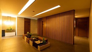 A modern lobby with a reception desk, potted plants, and a wooden partition. - Mateus hotel (Ghazir)