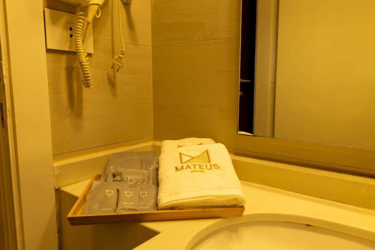 A hotel bathroom with a towel rack holding a towel and a tray with toiletries.