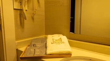 A hotel bathroom with a towel rack holding a towel and a tray with toiletries.