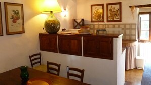 A rustic kitchen with wooden cabinets, a dining table with chairs, and a hanging light fixture. - Panoramic holiday apartment Torre Colombaia 4+2 pax (Spoleto)