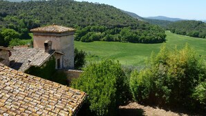 A rustic building with a tiled roof, surrounded by lush greenery and rolling hills. - Panoramic holiday apartment Torre Colombaia 4+2 pax (Spoleto)