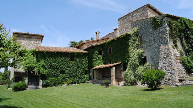 A stone building with ivy-covered walls and a tiled roof, surrounded by a well-maintained lawn. - Panoramic holiday apartment Torre Colombaia 4+2 pax (Spoleto)