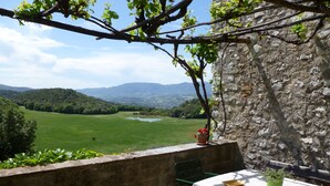 A terrace with a table and chairs, overlooking a green field and distant mountains. - Panoramic holiday apartment Torre Colombaia 4+2 pax (Spoleto)