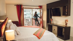 A hotel room with a large bed, a TV mounted on the wall, and a balcony with red curtains. - Altipacha Ayacucho Hotel (Ayacucho)