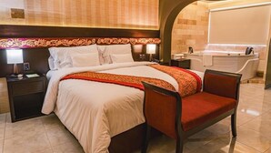 A hotel room with a bed, a chair, a nightstand, a lamp, a desk, and a bathroom with a bathtub and sink. - Altipacha Ayacucho Hotel (Ayacucho)