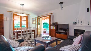 A living room with a checkered floor, a dining table with chairs, a sofa, a television, and a fireplace. -  Quiet family Villa in Pollensa countryside with pool,  just 3 km from town (pollensa)