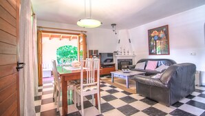A living room with a checkered floor, a sofa, a dining table with chairs, a fireplace, and a painting on the wall. -  Quiet family Villa in Pollensa countryside with pool,  just 3 km from town (pollensa)