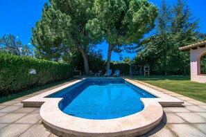 Relax by the pool surrounded by lush greenery and comfortable lounge chairs.