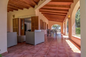 Relax on the covered patio with a view of the surrounding landscape, featuring a dining table and comfortable seating.
