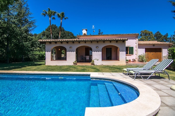 Relax by the pool surrounded by lush greenery and palm trees.