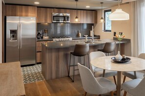 A modern kitchen with a central island, stainless steel appliances, and a dining area with chairs and a table. - Frida Boutique Stays by Viadora (Mexico City)