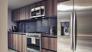 Una cocina moderna con refrigerador de acero inoxidable, horno empotrado, microondas y estufa a gas.