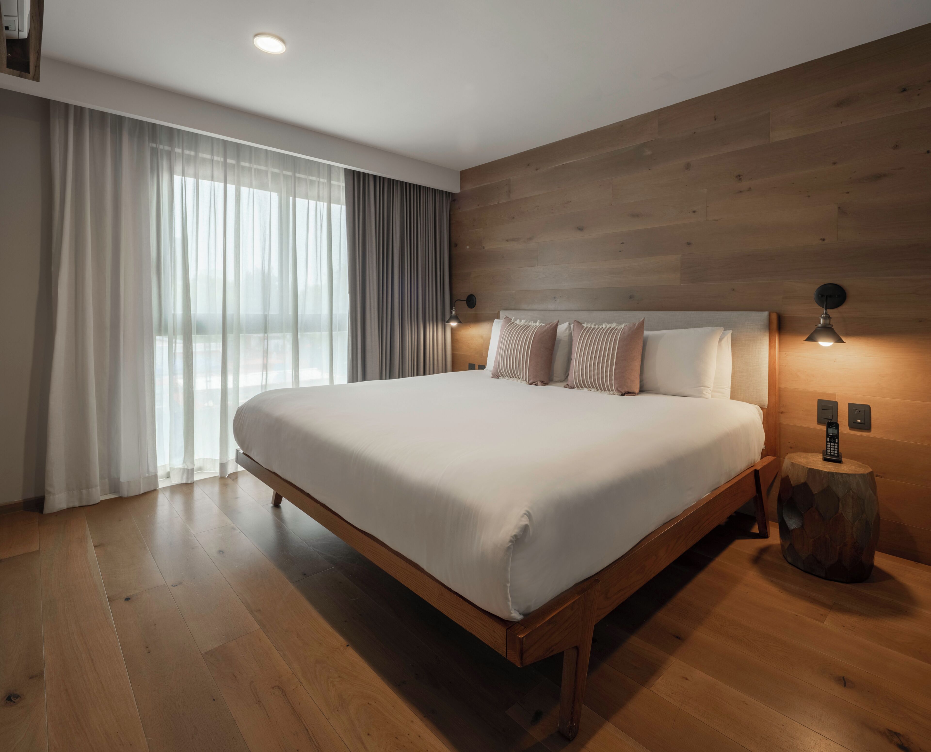 Un dormitorio moderno con una cama grande, cabecera de madera y piso de madera.