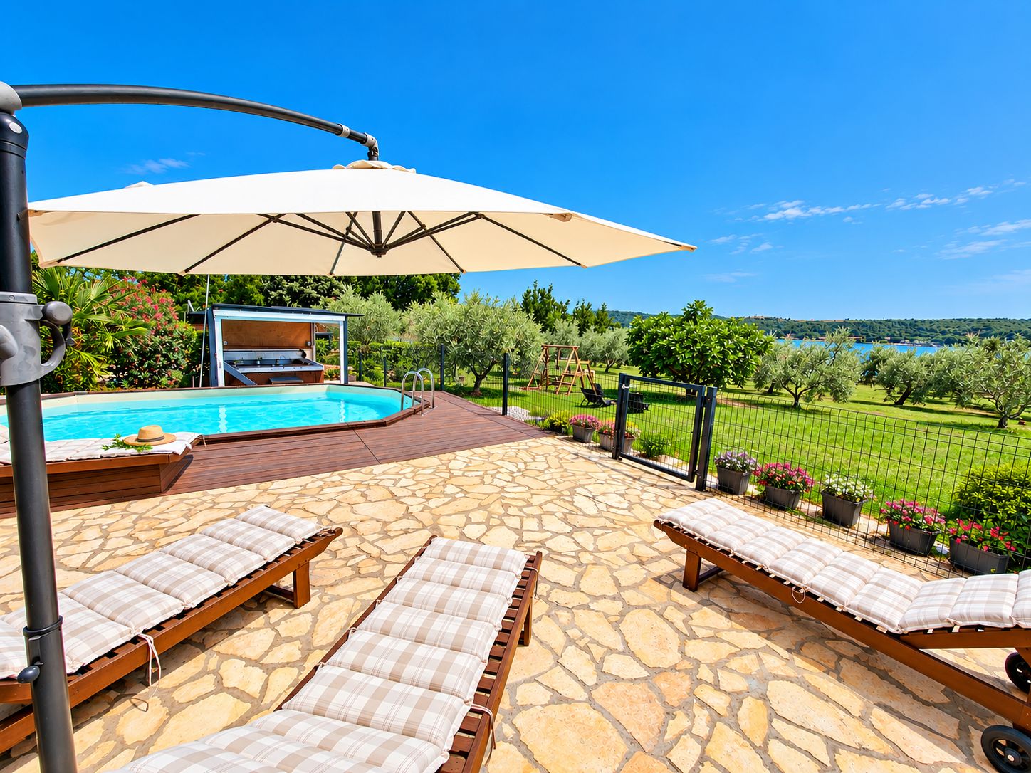 A poolside area with lounge chairs, a covered seating area, and a view of the landscape.