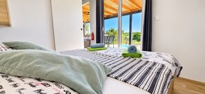 A hotel room with a bed, a window, and a view of an outdoor area.