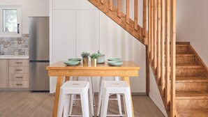Une cuisine moderne avec un escalier en bois, des armoires blanches et un réfrigérateur en acier inoxydable.