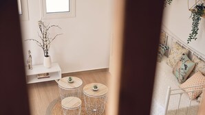 Une pièce avec un lit blanc, une chaise blanche et une petite table blanche sur laquelle est posée une plante.