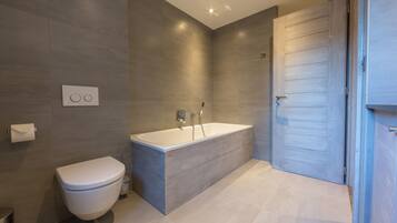Une salle de bain moderne équipée de toilettes, d’une baignoire et d’une douche.