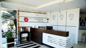 Un comptoir d’accueil d’hôtel au design moderne, orné d’un logo, d’une croix et d’horloges indiquant le nom de différentes villes.