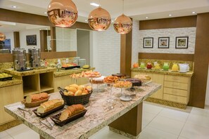 A buffet area with various food items, including bread, pastries, and fruit.