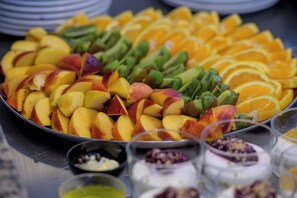 Una bandeja con una selección de frutas: manzanas, naranjas y kiwi en rodajas.