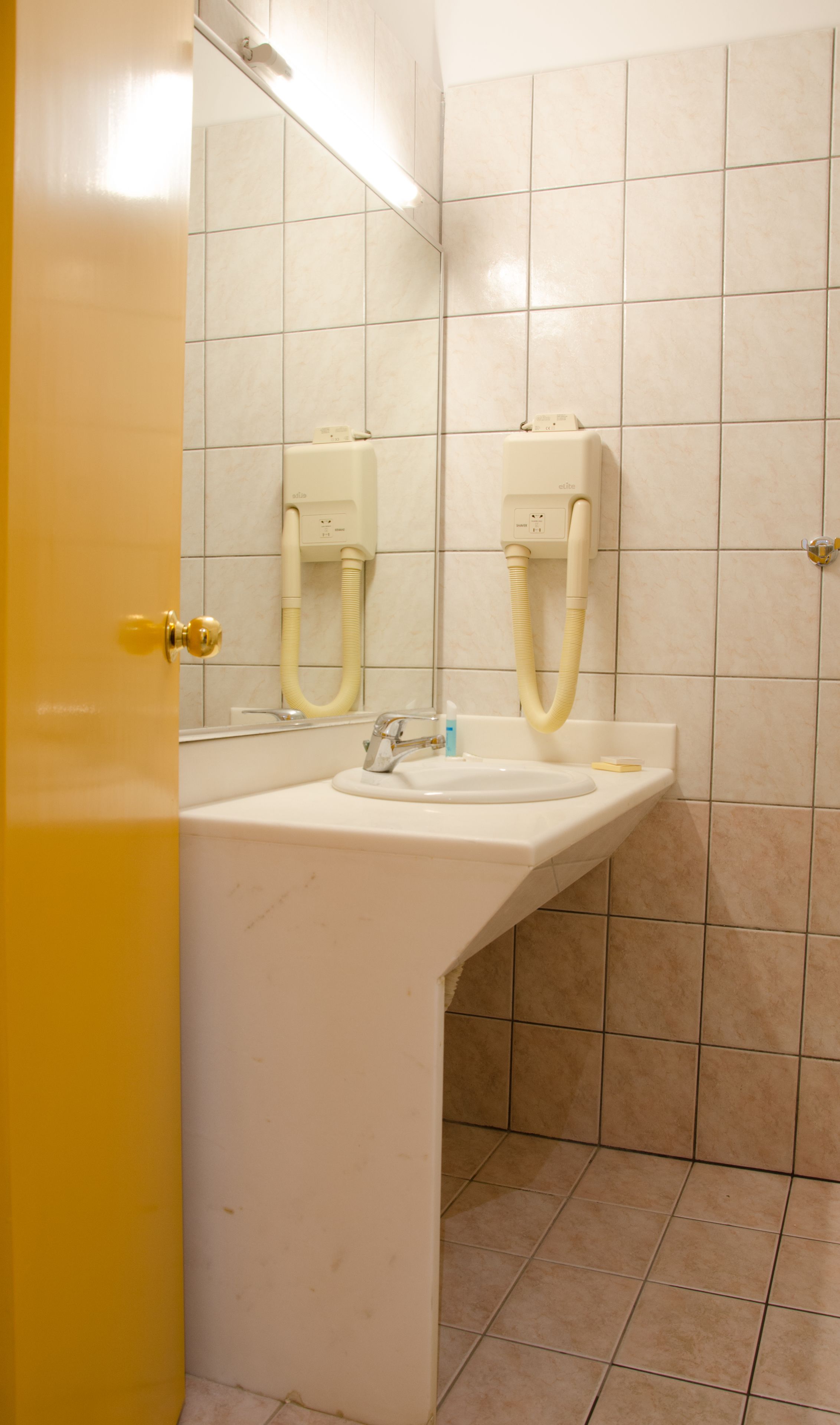 A bathroom with a white sink, a mirror, and two towel racks.