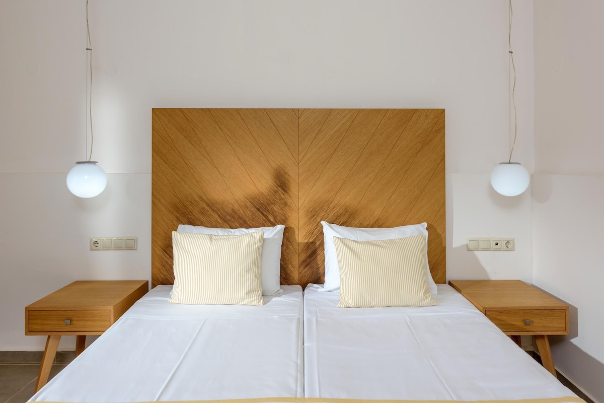 A double bed with a wooden headboard, two bedside tables, and two wall-mounted lamps.