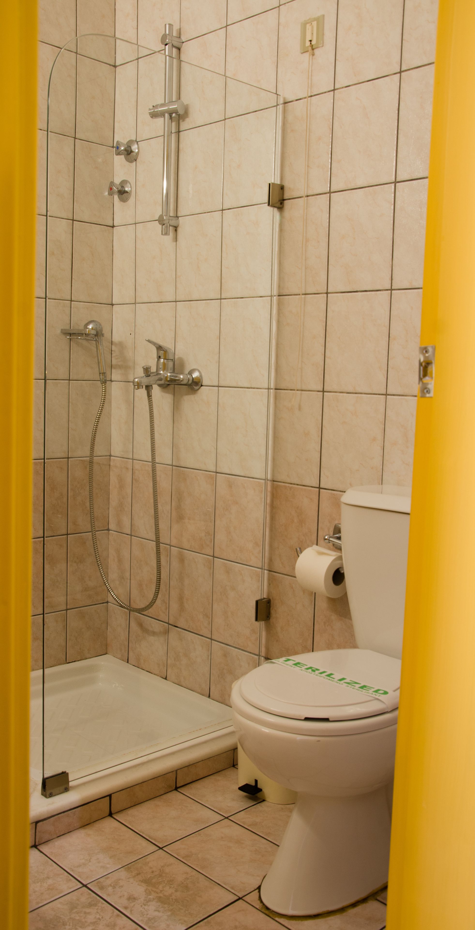 A bathroom with a shower, toilet, and a tiled floor.