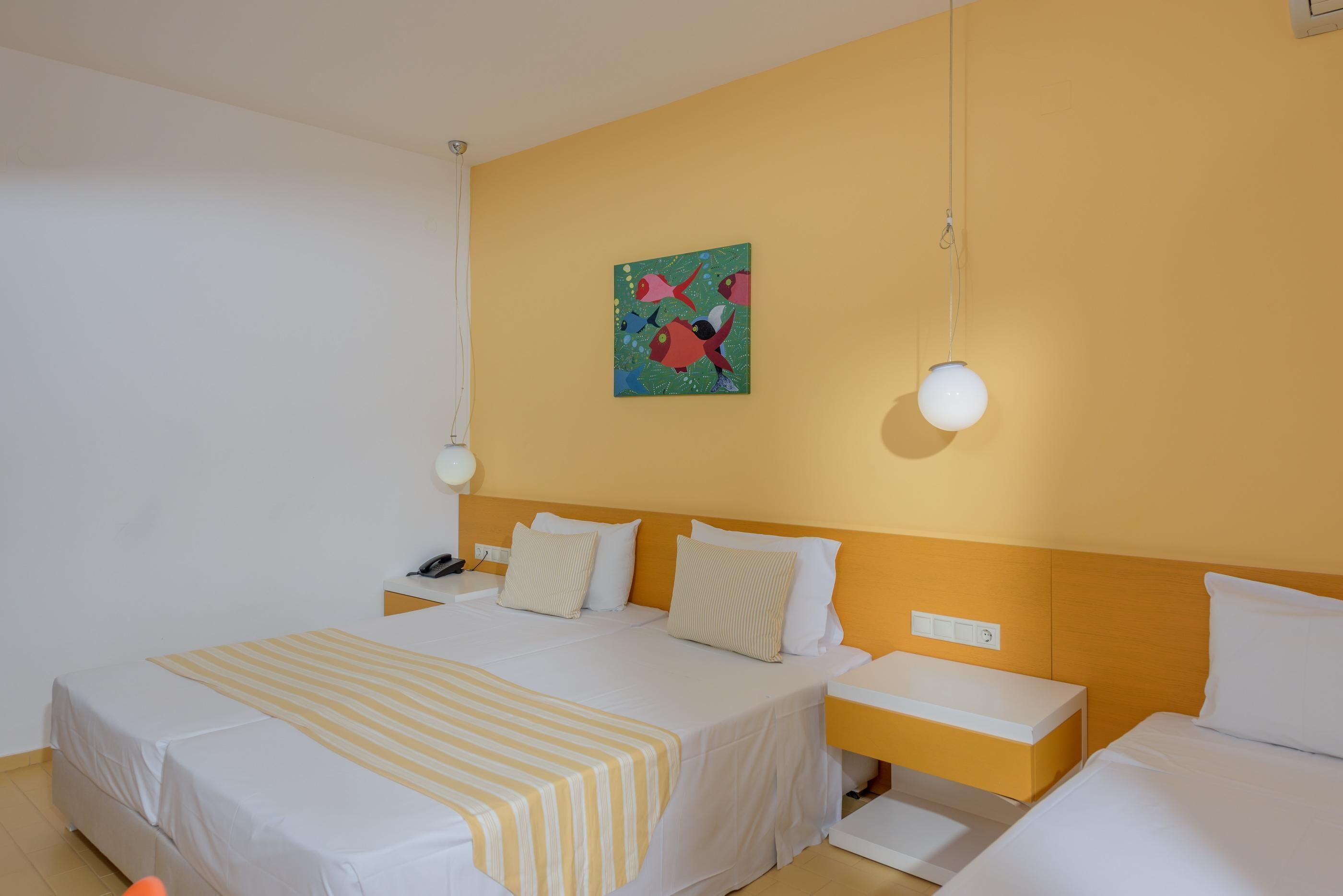 A hotel room with a bed, bedside tables, a nightstand, a painting, and a hanging light fixture.