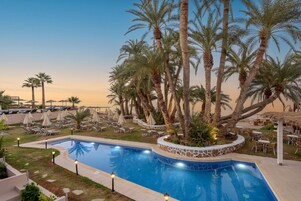 Una piscina al aire libre, sombrillas, sillones reclinables de piscina