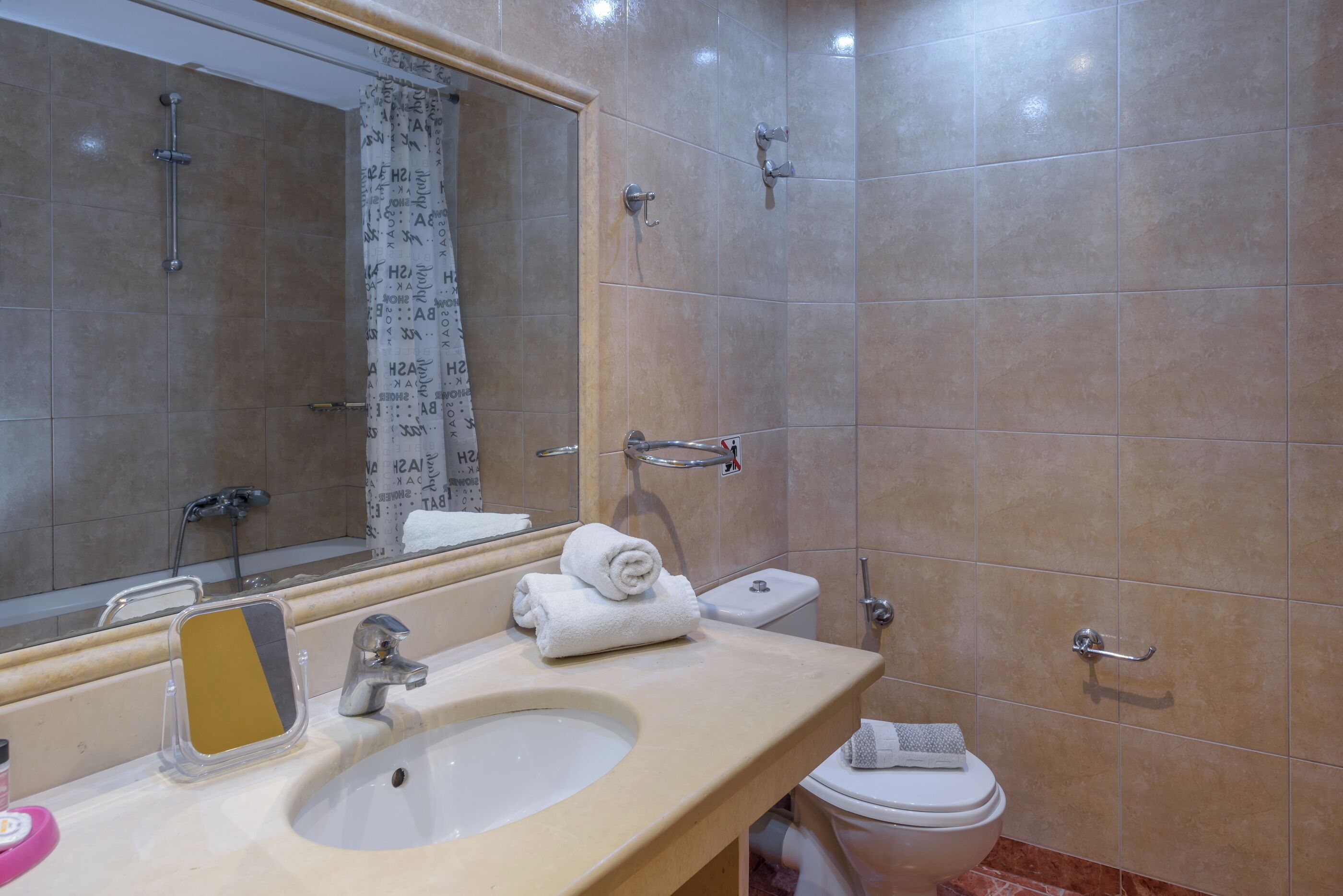 A bathroom with a sink, mirror, towel rack, and toilet.