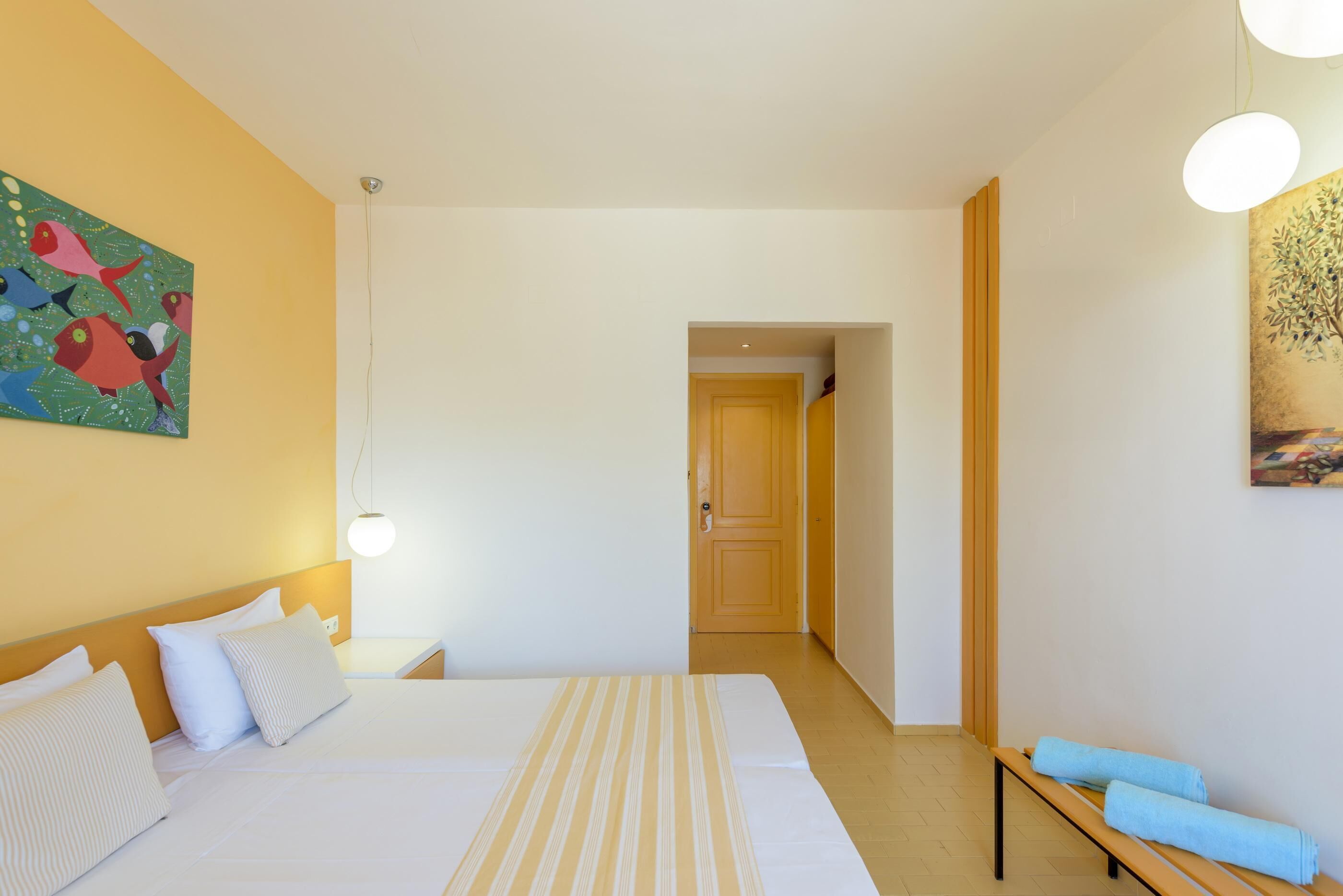 Una habitación de hotel con una cama grande, una mesita de noche, una lámpara y un cuadro en la pared.