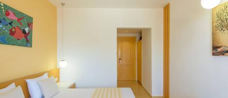 Una habitación de hotel con una cama grande, una mesita de noche, una lámpara y un cuadro en la pared.
