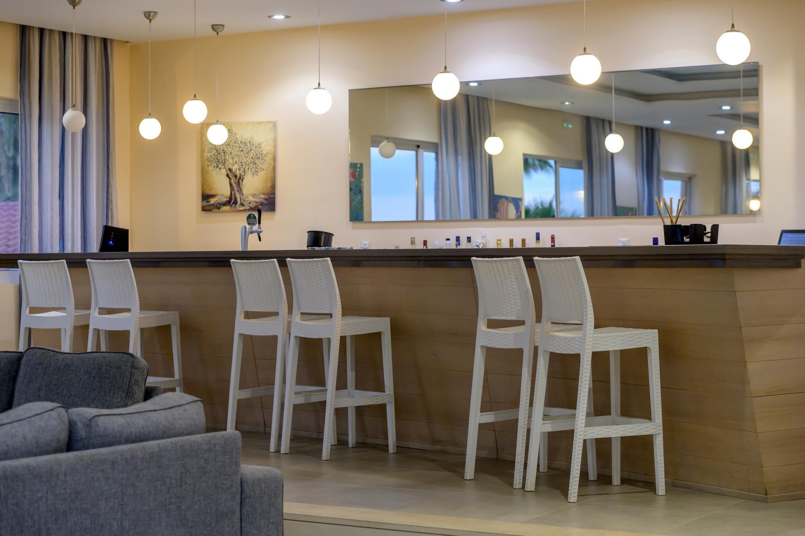 A reception area with a counter, white chairs, a sofa, and a large mirror.
