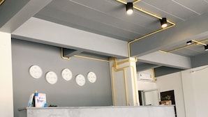 Un comptoir d’accueil avec un plateau en marbre, une horloge murale et une petite plante posée sur le comptoir.