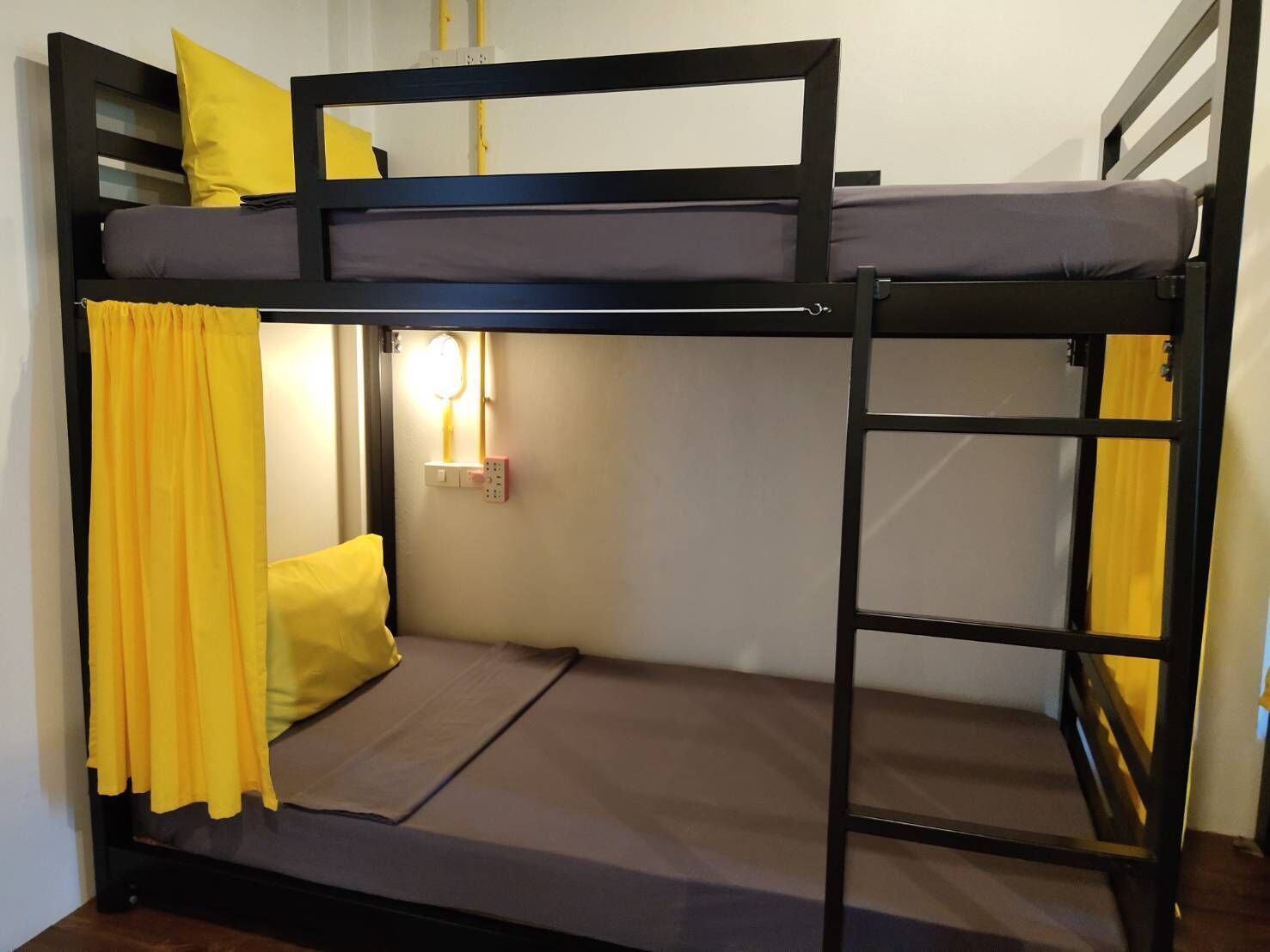 A bunk bed with a ladder, a bedside table with a lamp, and yellow curtains.