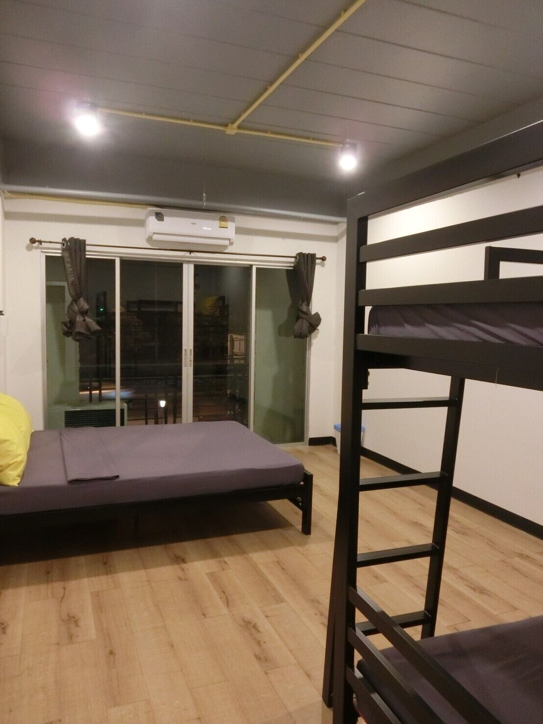 Ein Zimmer mit Etagenbett, Einzelbett, Schiebetür und einem kleinen Tisch.