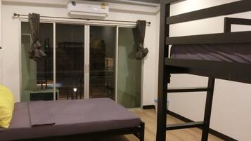 Ein Zimmer mit Etagenbett, Einzelbett, Schiebetür und einem kleinen Tisch.